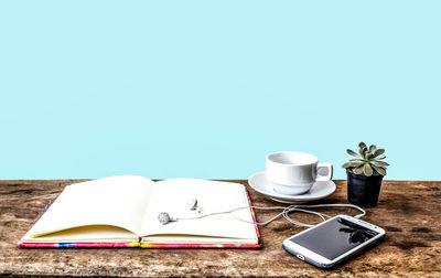 Close-up of mobile phone and book on table against blue background