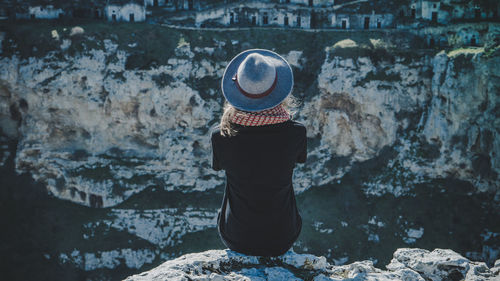 Rear view of a woman sitting on rock