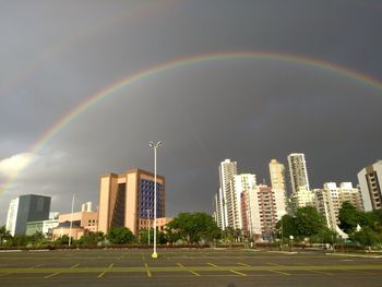 Rainbow over city buildings against sky