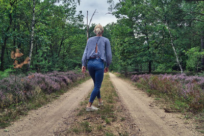 Rear view of woman walking on street amidst trees