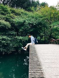 Man standing on footbridge over lake