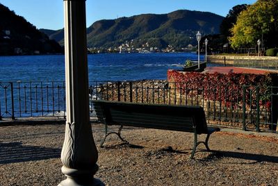 Empty chairs and table by sea against sky