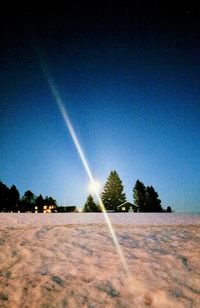 Trees on field against clear blue sky