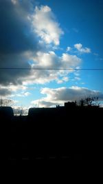 Low angle view of power lines against cloudy sky