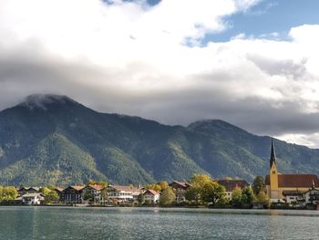 Scenic view of mountains, lake and town against sky