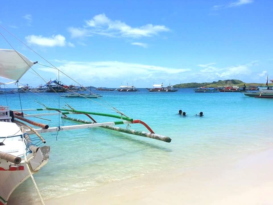 BOATS MOORED IN SEA AGAINST SKY