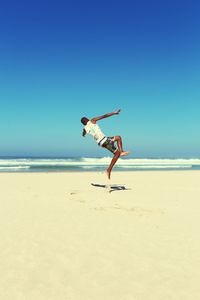 Man jumping at beach against sky