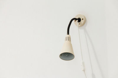 Close-up of lamp mounted on white wall