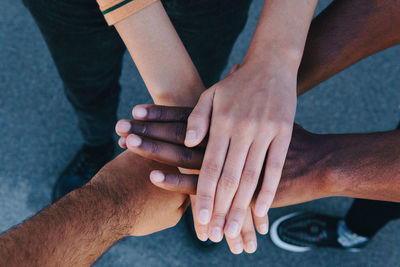 From above cropped unrecognizable african american people putting hands together standing on the street