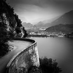 Scenic view of road near lake by mountains against sky