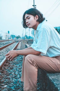 Young man sitting on railroad track