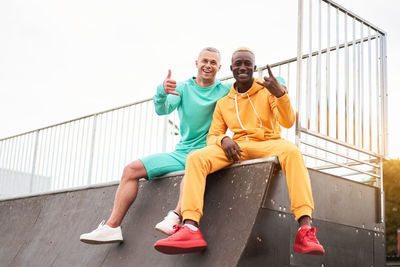 Portrait of happy friends sitting on railing