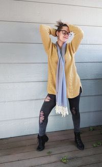 Fashion shot of young woman in edgy fall outfit, yellow sweater, combing fingers through short hair