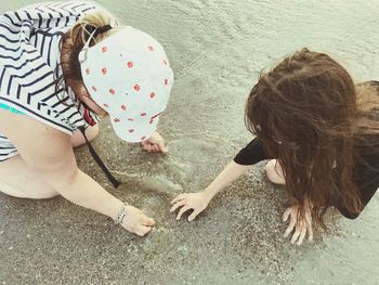 High angle view of mother with daughter playing at beach 