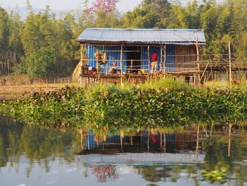 Built structure by lake against trees and plants