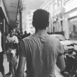 Rear view of man standing on road in city