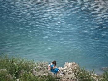 High angle view of woman sitting on sea shore