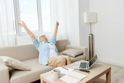 Woman using digital tablet while sitting on sofa at home