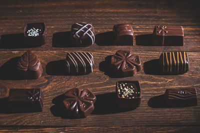 Pralines on wooden base, deep shadows, close up. sweet and chocolate concept.