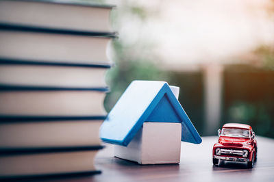 Close-up of model house and books with toy car on table