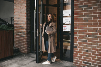 Portrait of woman standing against door