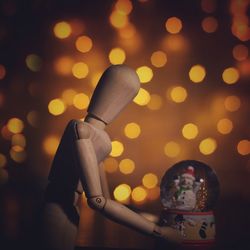 Close-up of figurine with snow glob against illuminated lights