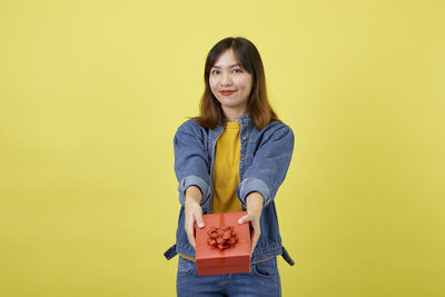 Portrait of a smiling young woman against yellow background