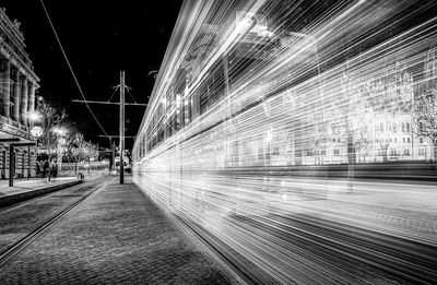 Light trails on street amidst illuminated buildings at night