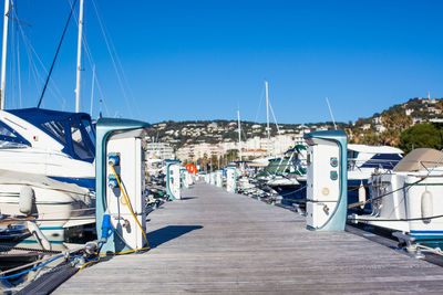 Sailboats moored in city against clear blue sky