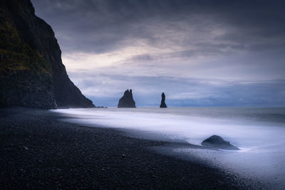 Tormy morning at the shore of reynisfjara black sand beach looking to reynisdrangar cliff in iceland