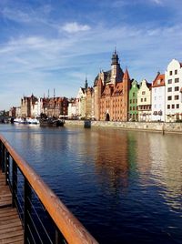 View of buildings by river against sky in city