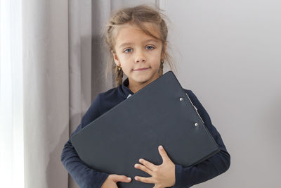 Portrait of cute girl standing against wall