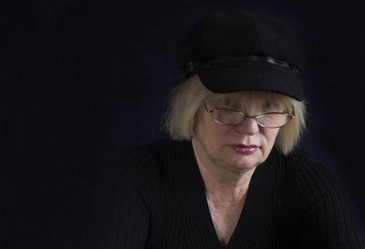 Portrait of mature woman with cap against black background