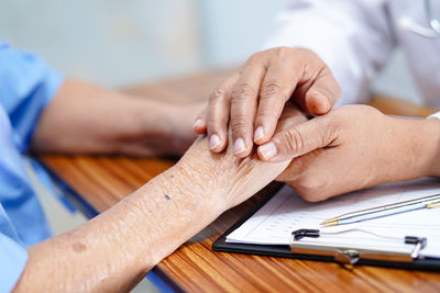 Close-up of man holding hands on table