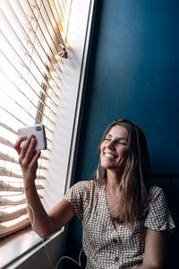 Woman doing video while sitting by window