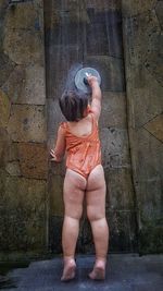 Rear view of girl standing against wall