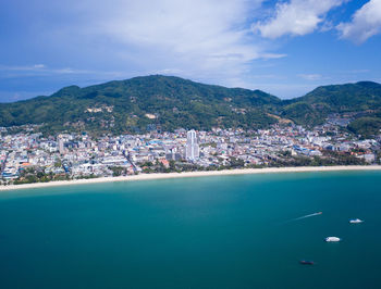 Aerial view of city by sea against sky