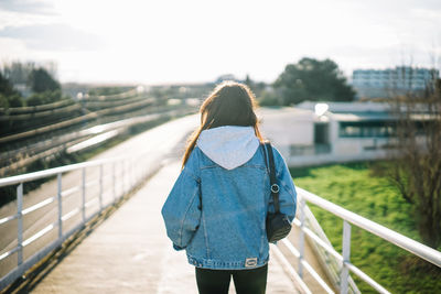 Rear view of woman walking on footbridge