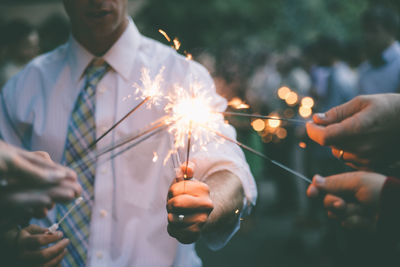 Close-up of friends igniting sparklers at party