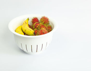 High angle view of fruits in bowl against white background