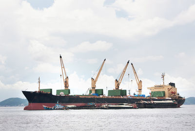 Cranes at commercial dock against sky