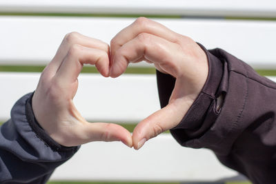 Cropped image of couple forming heart shape against wall