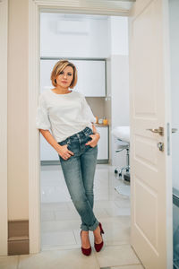 Portrait of young woman standing against wall