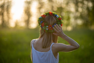 Midsection of woman standing by red flowering plant