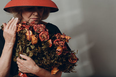 Midsection of woman holding red flowering plant