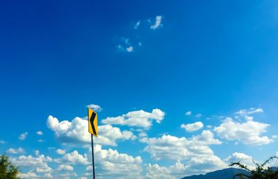 Low angle view of yellow flag against blue sky