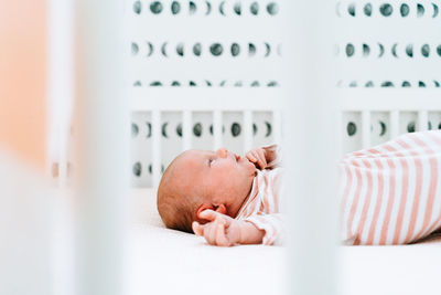 Sideview of a newborn girl laying in her modern crib