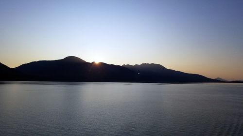 Scenic view of silhouette mountains against clear sky during sunset