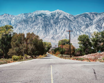 Road amidst trees and mountains against sky