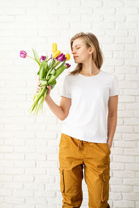 Young woman wearing blank white t-shirt holding tulips flowers. mock up design